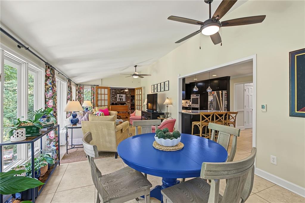 Dining area with a blue round table, large windows, and an open view into the kitchen.