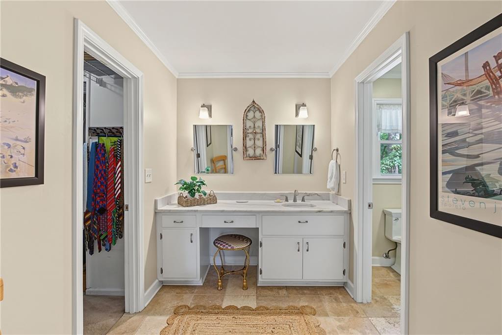 Bathroom vanity with two sinks and mirrors, opening to a walk-in closet and separate toilet room.