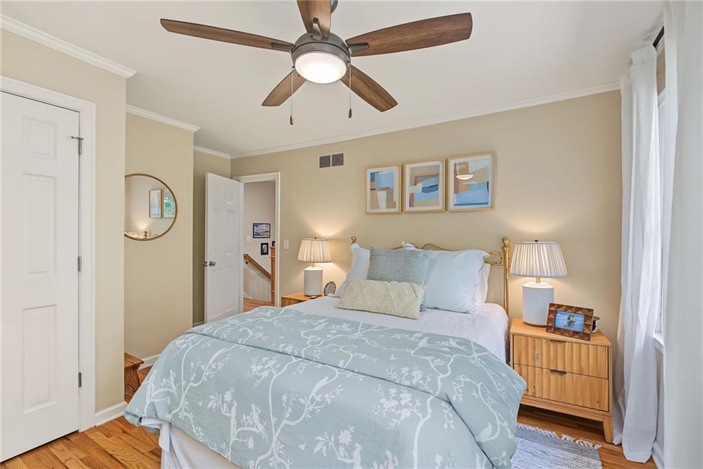 Furnished bedroom with pale blue bedding, wooden nightstands, and a ceiling fan.