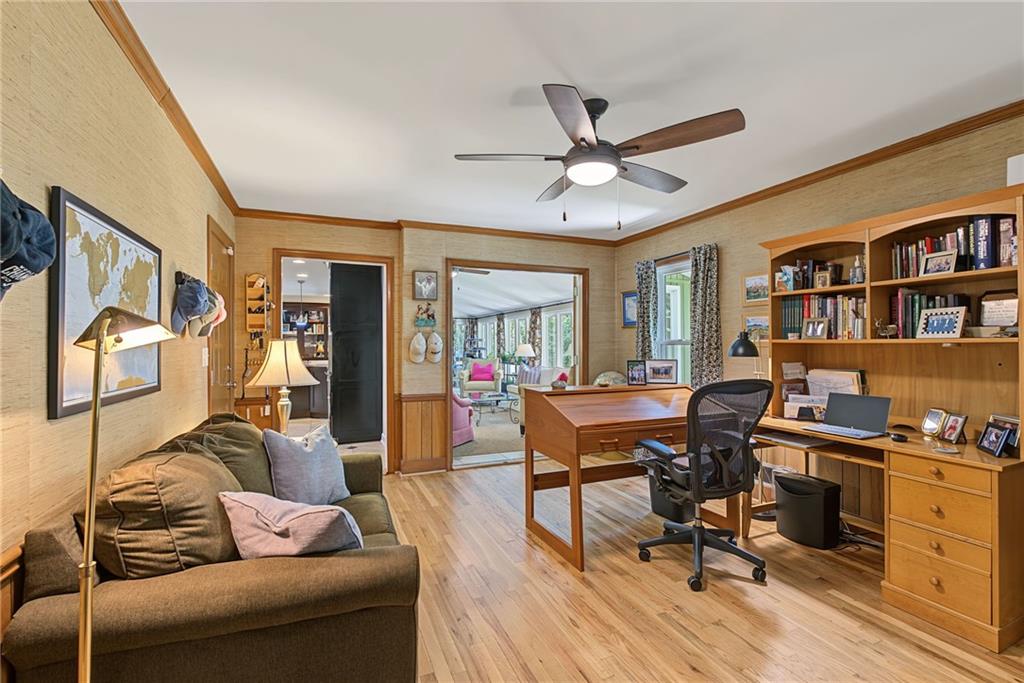 Home office with built-in wooden desk and bookshelves beside a brown sofa.