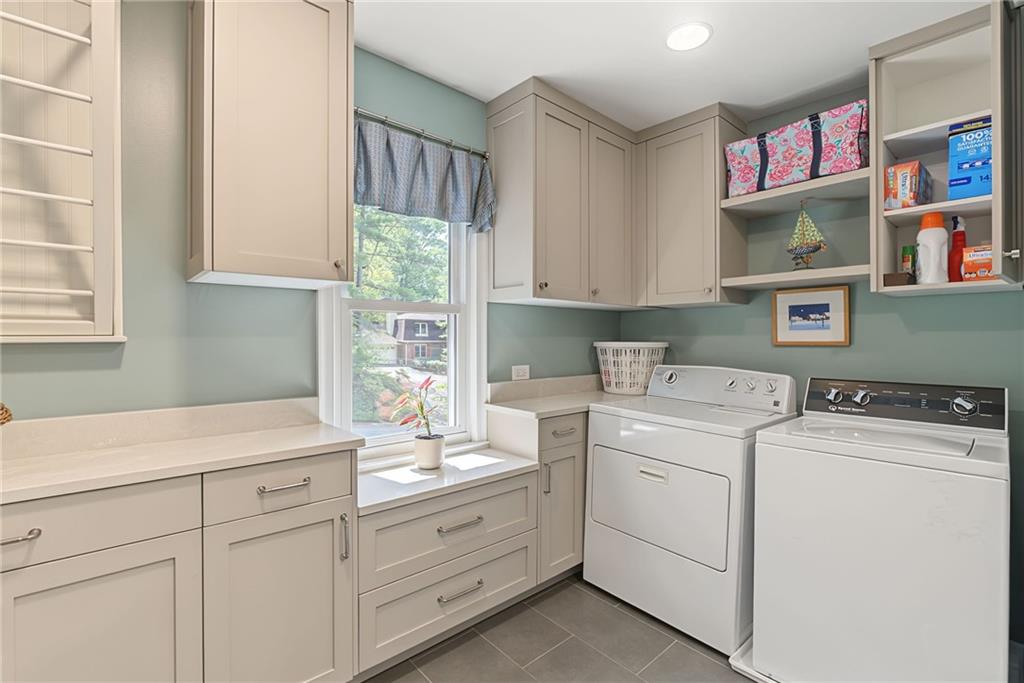 Laundry room with white washer and dryer, built-in cabinetry, and a window above the counter.