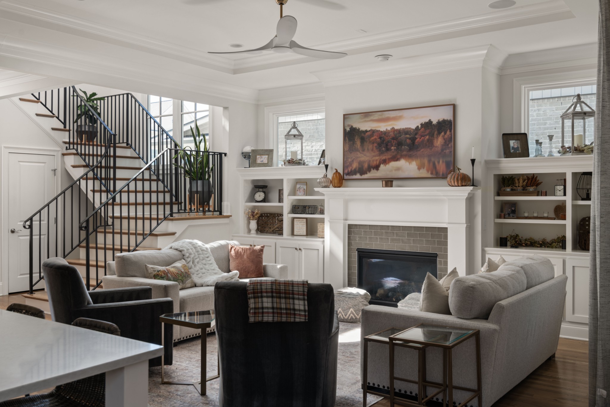 Living room with a fireplace, built-in shelves, and a staircase with black railings.