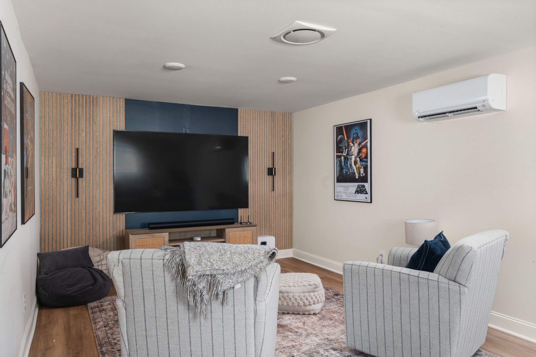 Living room with a large TV on a wood-slat feature wall and two upholstered armchairs.