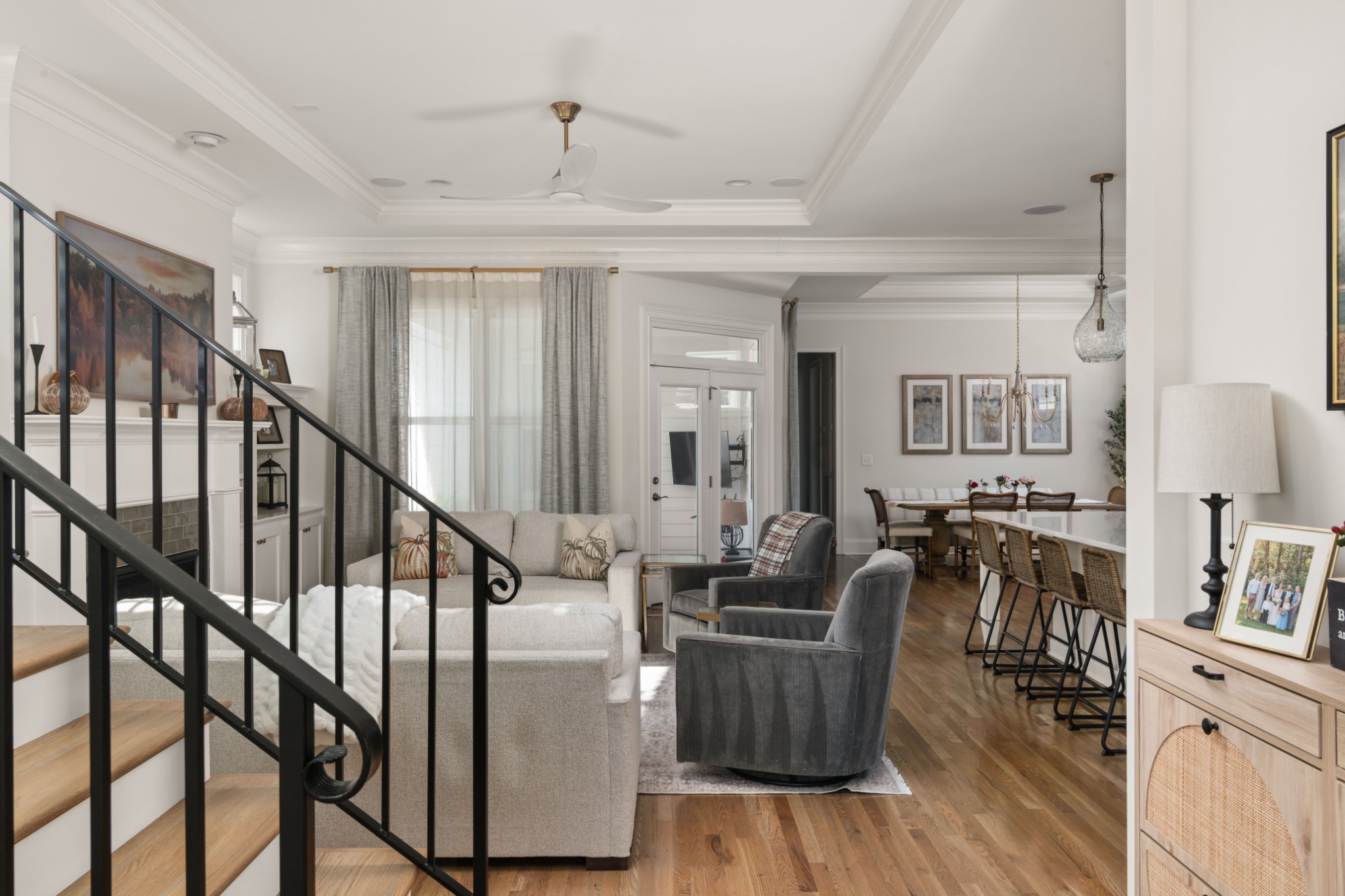 Open living and dining room with a staircase, hardwood floors, and neutral furnishings.