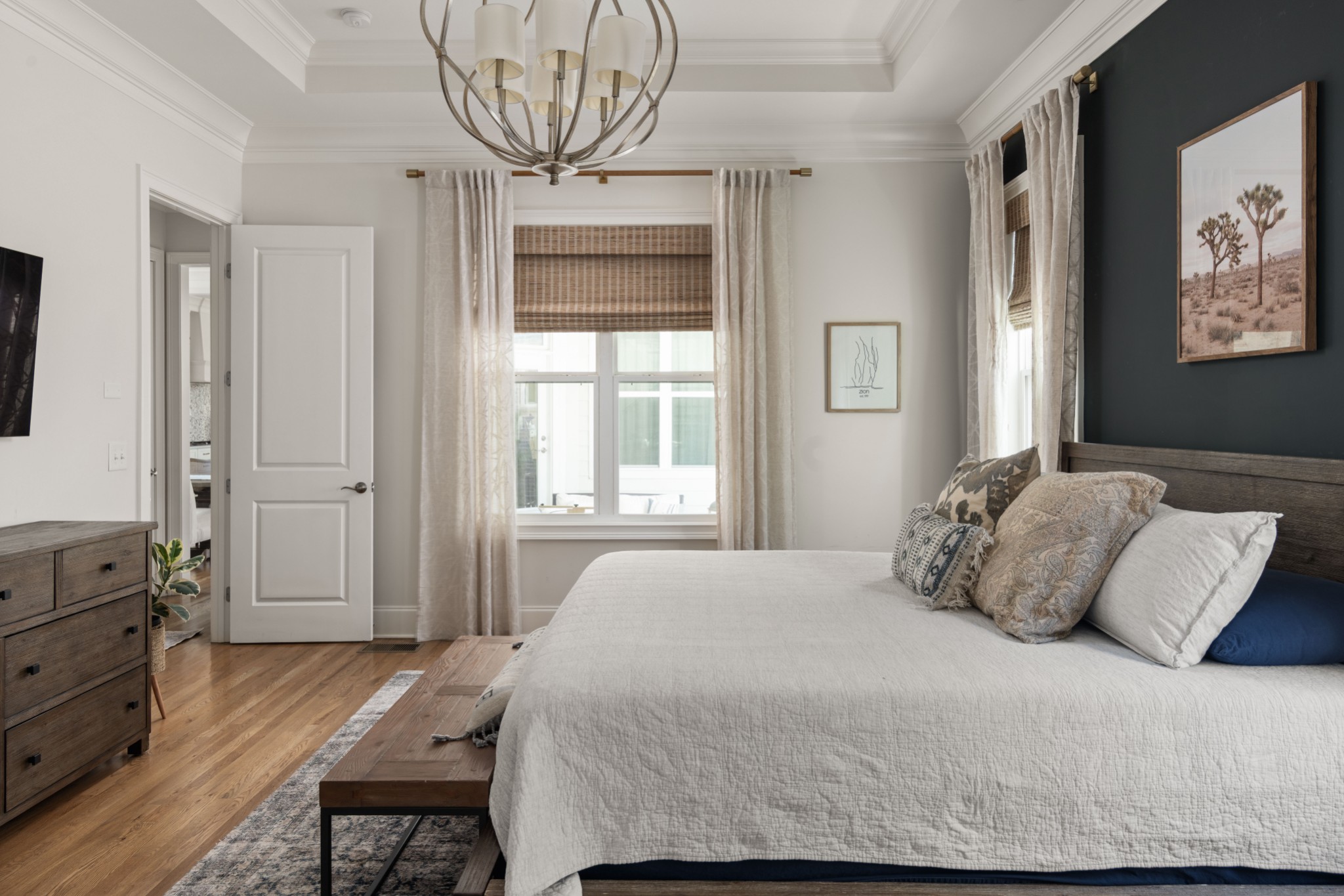 Bedroom with a white quilted bed, dark accent wall, and large curtained window.