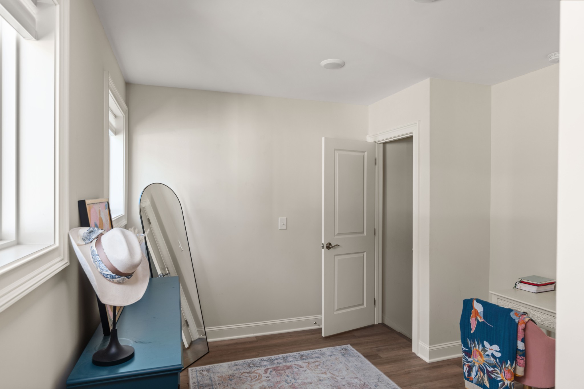 Dressing area with a leaning mirror, blue dresser, and open door.