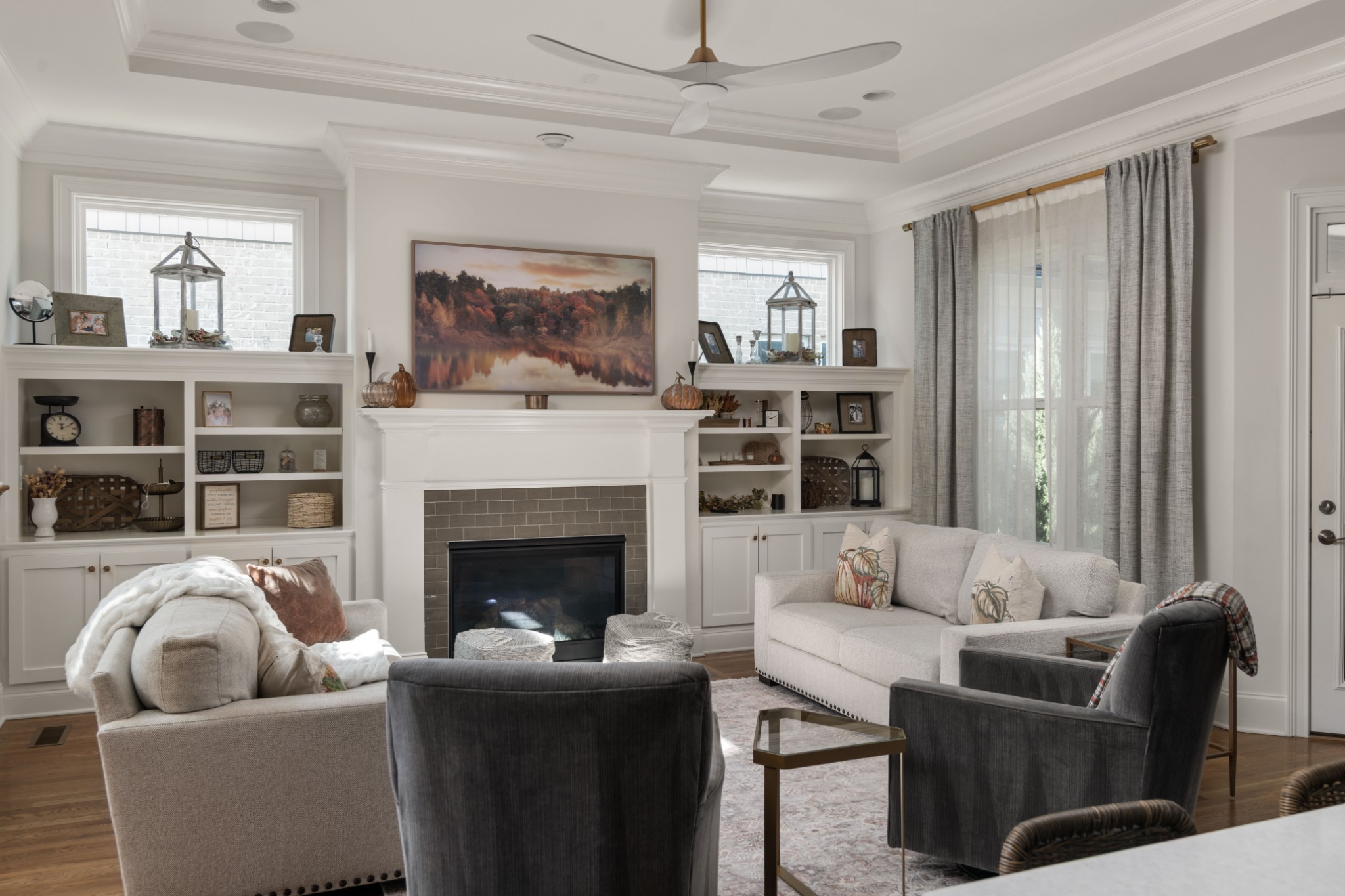 Living room with a tiled fireplace, built-in shelves, and light sofas facing dark armchairs.