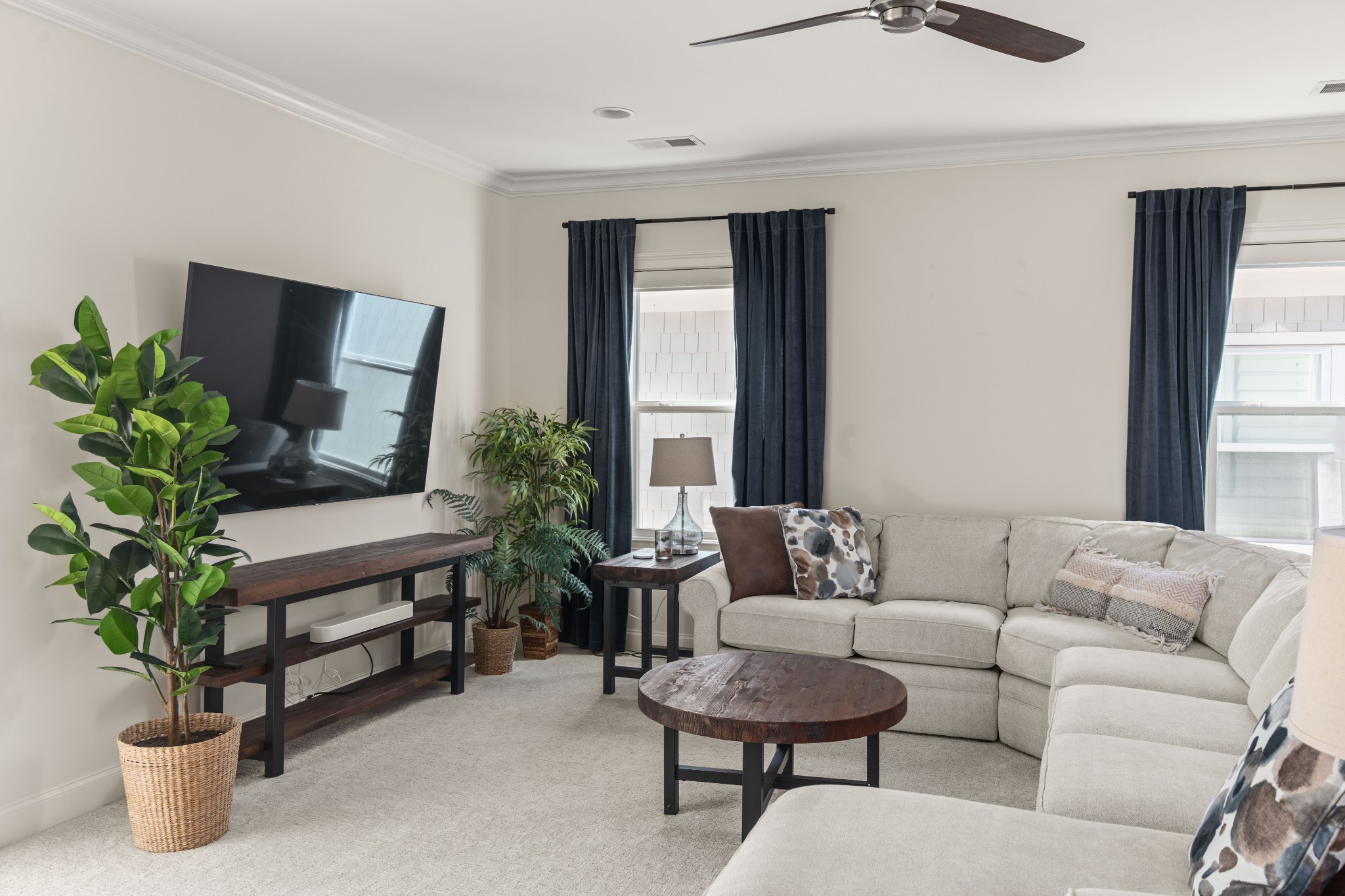 Staged living room with a cream sectional, dark wood coffee table, and navy curtains.