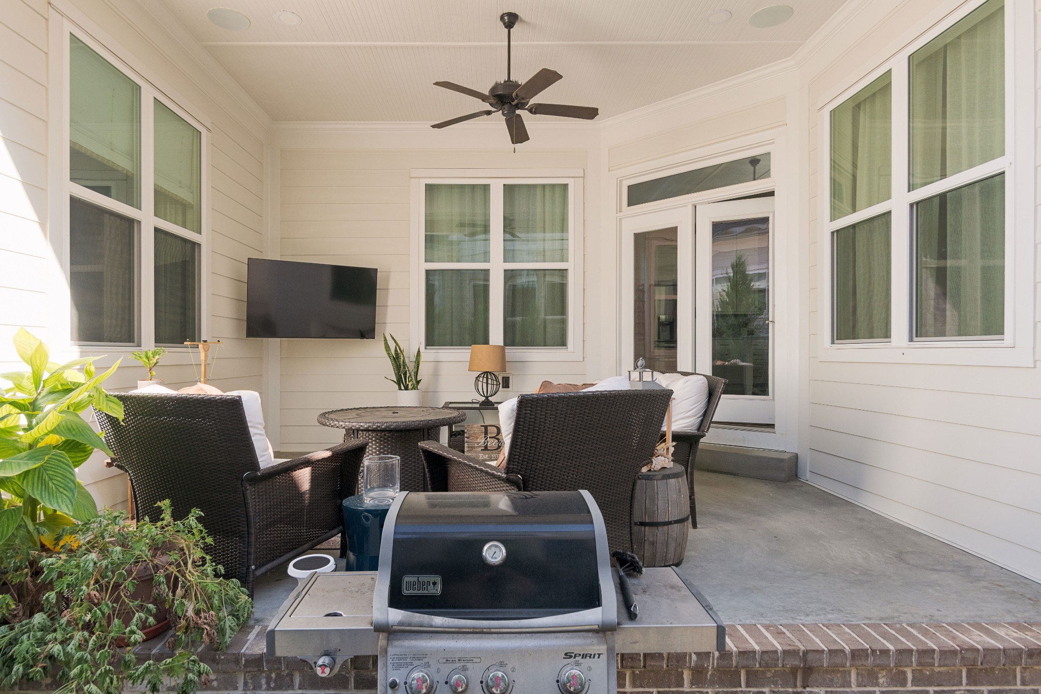 Covered patio with wicker seating, a ceiling fan, and a Weber grill.