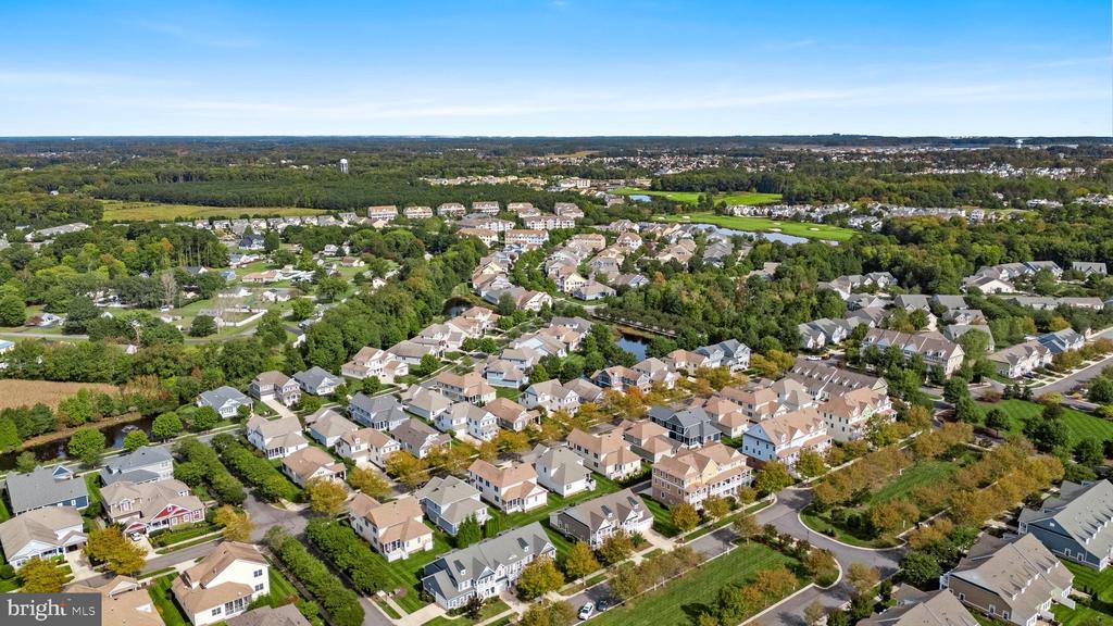 Aerial view of a residential neighborhood with tree-lined streets and a golf course beyond.