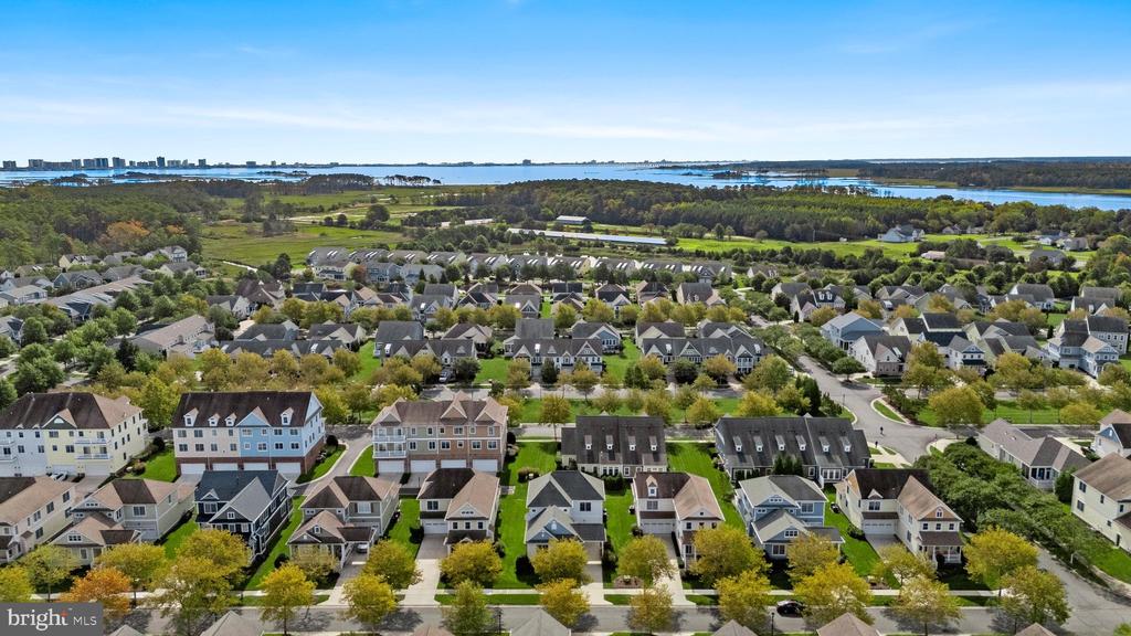 Aerial view of a coastal neighborhood with rows of homes and water in the distance.