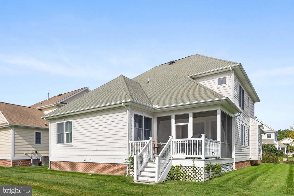 Rear exterior of a light-sided home with a screened porch and white steps.