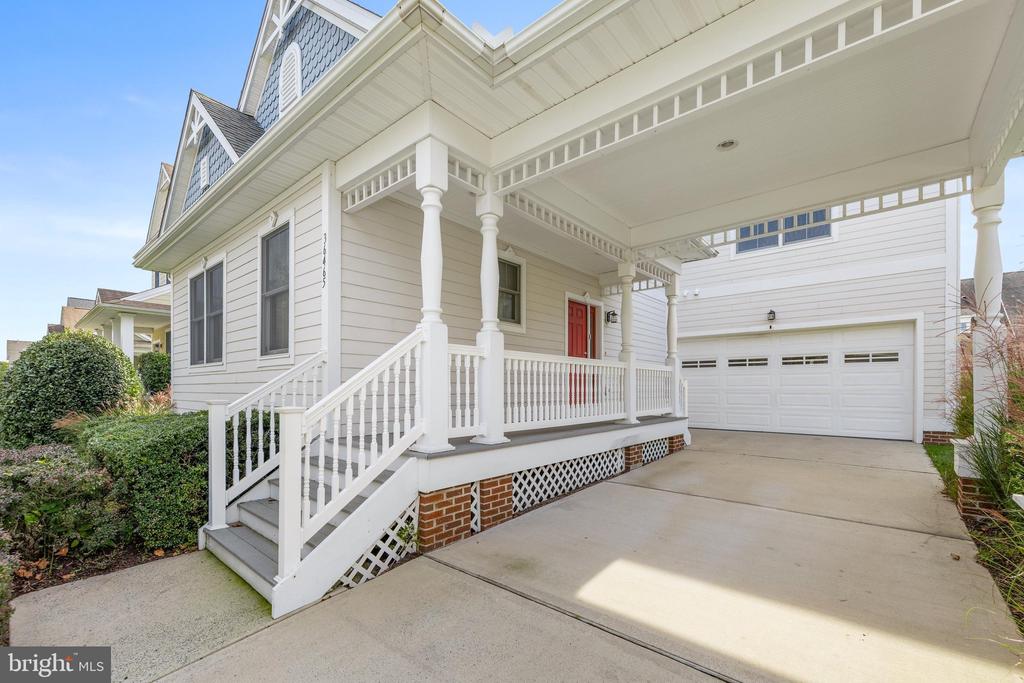 White coastal-style home with a covered porch, red front door, and attached garage.