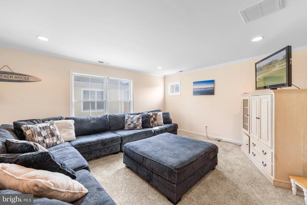 Living room with a dark sectional sofa, matching ottoman, and large windows.