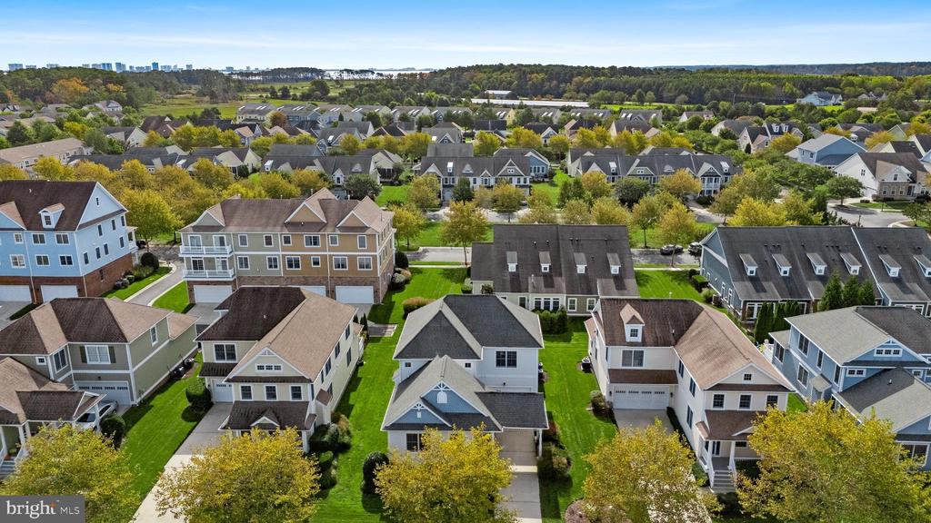 Aerial view of a suburban neighborhood with closely spaced homes, green lawns, and tree-lined streets.