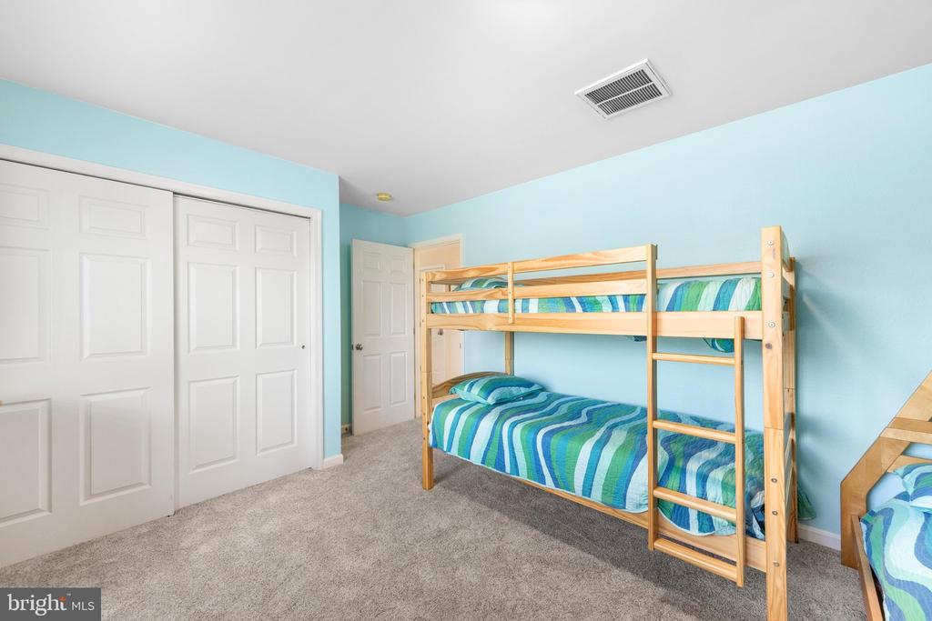 Bedroom with a wooden bunk bed, blue striped bedding, and light blue walls.
