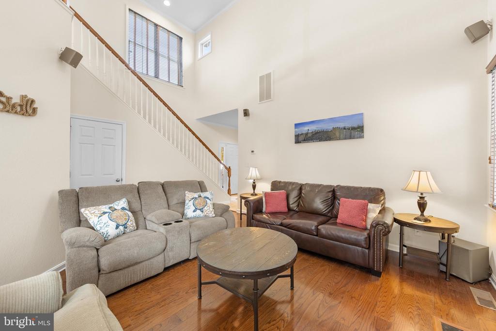 Living room with two sofas, a round coffee table, and a staircase rising to the second floor.