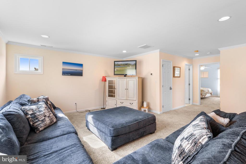 Living room with blue sectional sofas, a matching ottoman, and a light wood media cabinet.