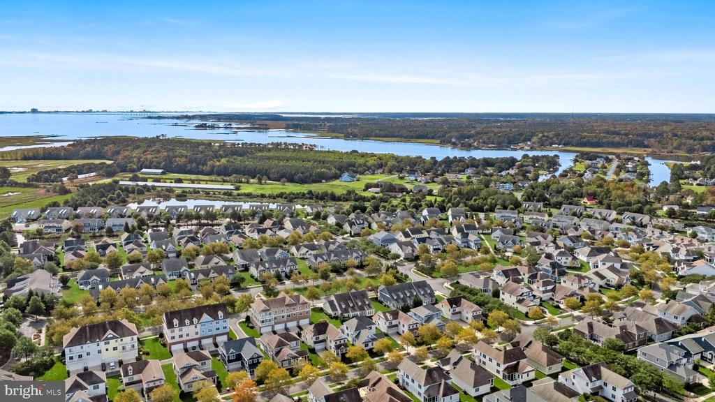Aerial view of a residential community beside a broad waterway, with rows of homes and green space.