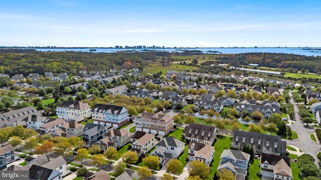Aerial view of a residential community with wooded areas and water in the distance.