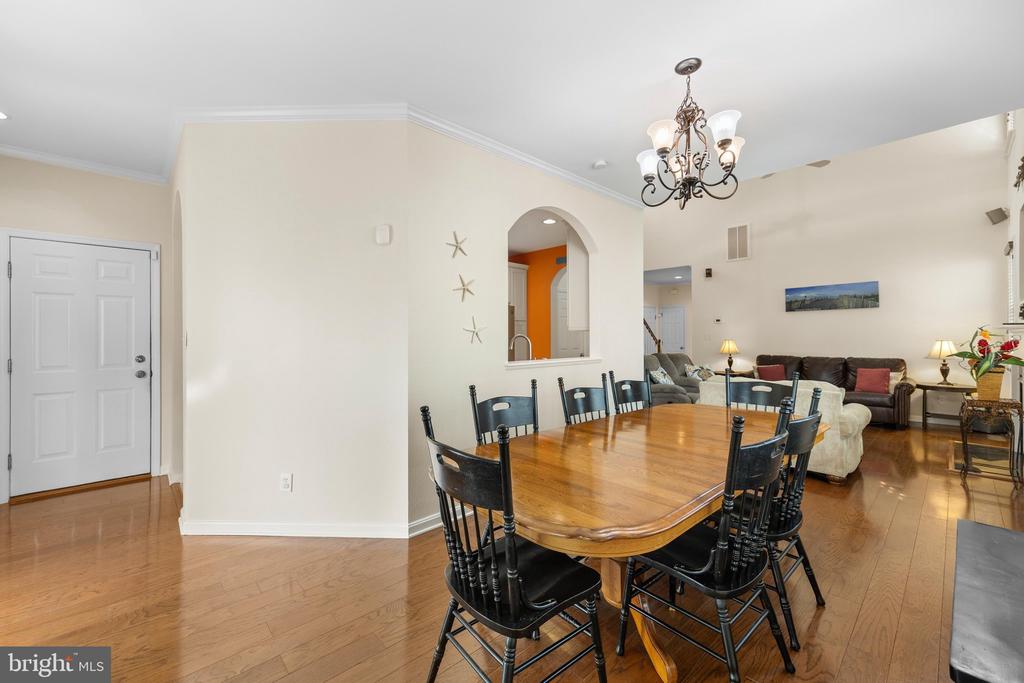Dining room with a wood table and black chairs, opening to a furnished living room.