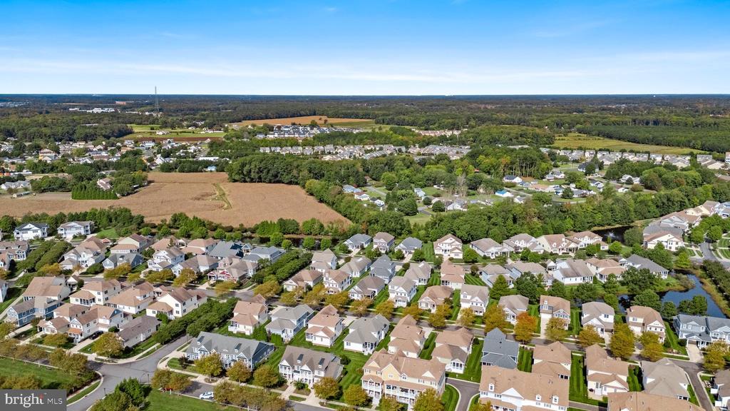 Aerial view of a residential neighborhood bordered by fields and wooded areas.