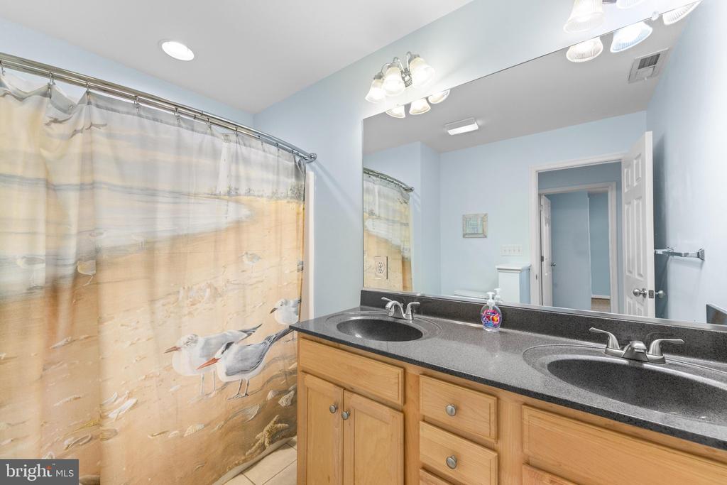 Bathroom with a double-sink vanity, wood cabinets, and a beach-themed shower curtain.
