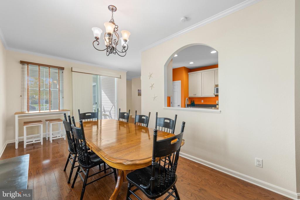 Dining room with a wooden table, black chairs, hardwood floors, and an arched kitchen pass-through.