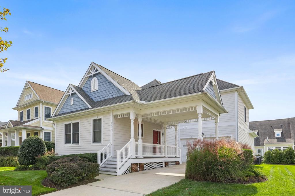 Light-sided home with blue scalloped gables, a covered porch, and an attached garage.