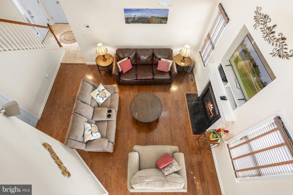Living room with leather and upholstered seating, wood floors, and a fireplace, viewed from above.