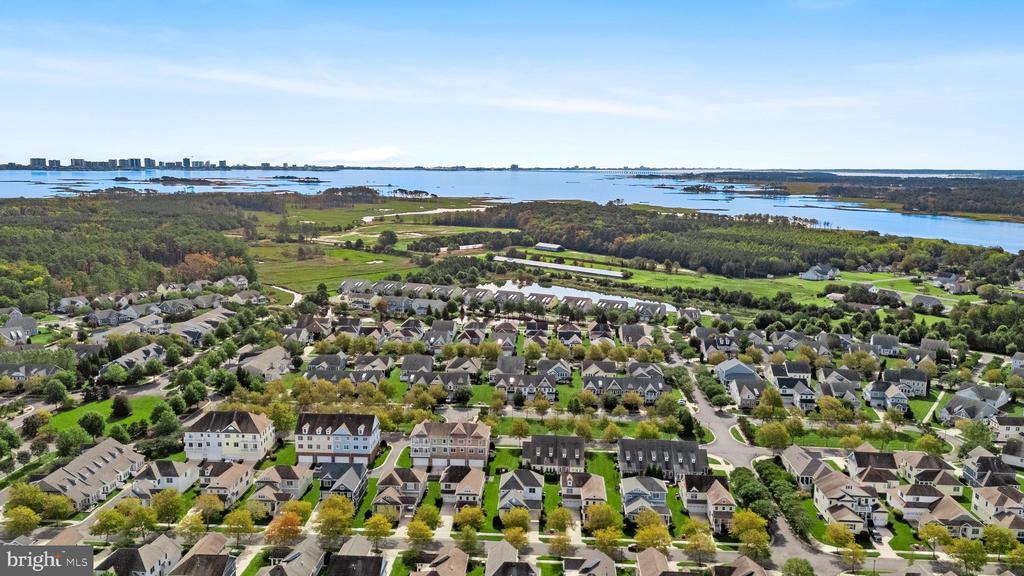 Aerial view of a coastal neighborhood beside a broad bay and marshland.