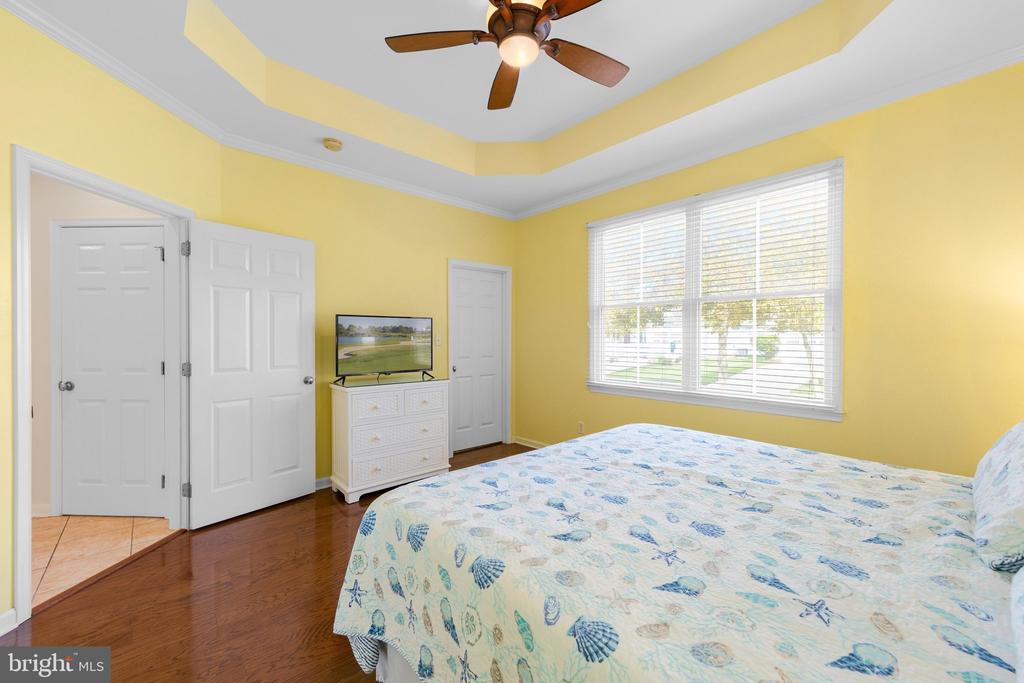 Bedroom with yellow walls, a tray ceiling, and a bed beside a large window.