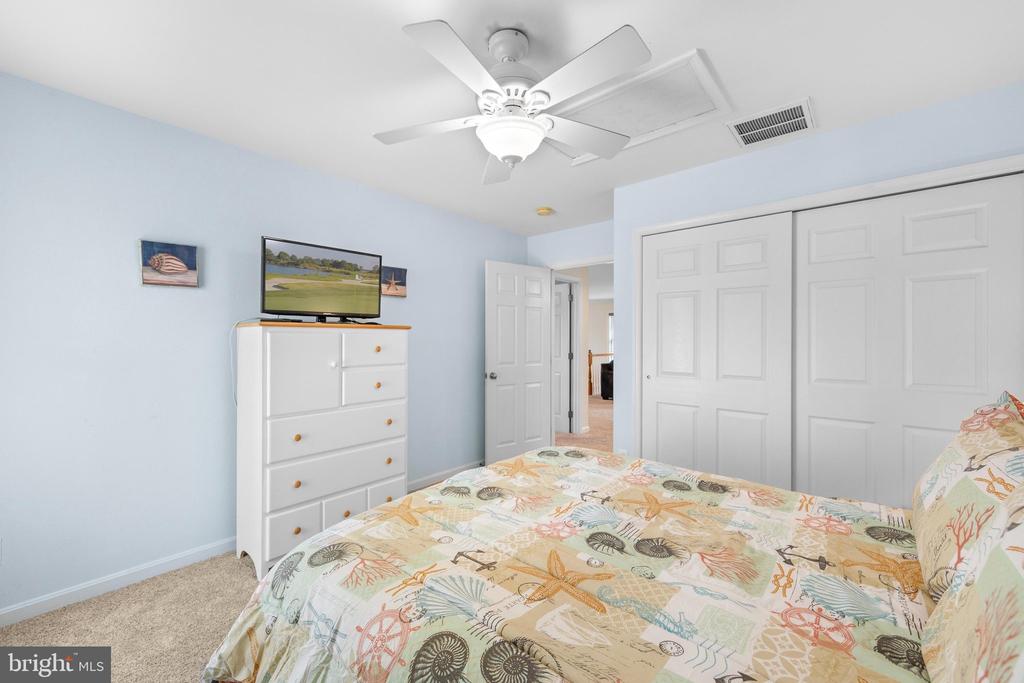 Bedroom with pale blue walls, a white dresser, and coastal-patterned bedding.