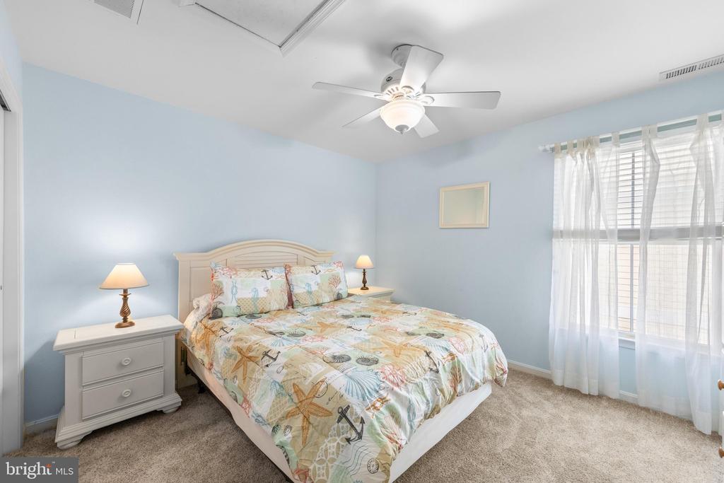 Bedroom with a queen bed, pale blue walls, and a large curtained window.