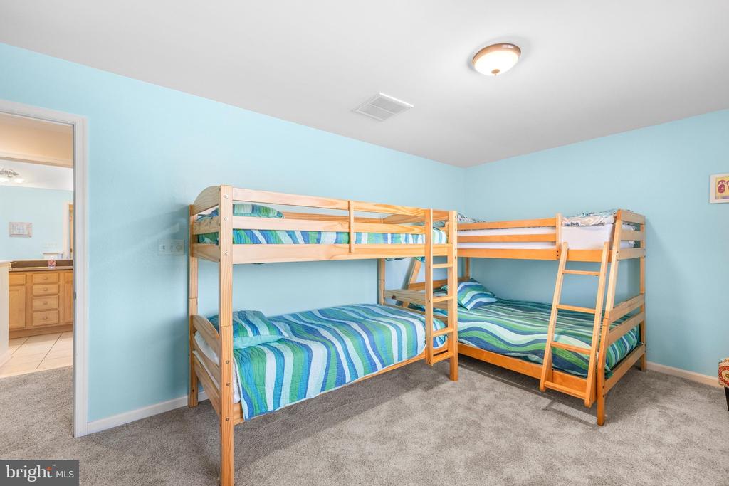Bedroom with two wooden bunk beds and blue-green striped bedding.