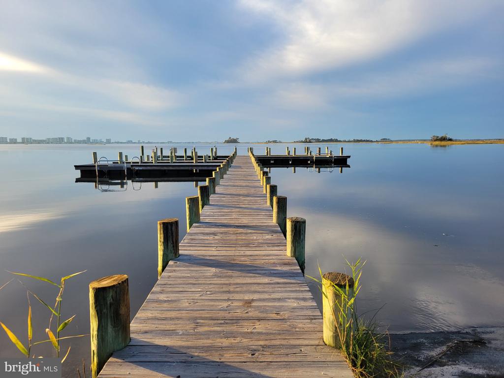 Wooden dock extends into a calm bay, with a floating pier and distant shoreline.