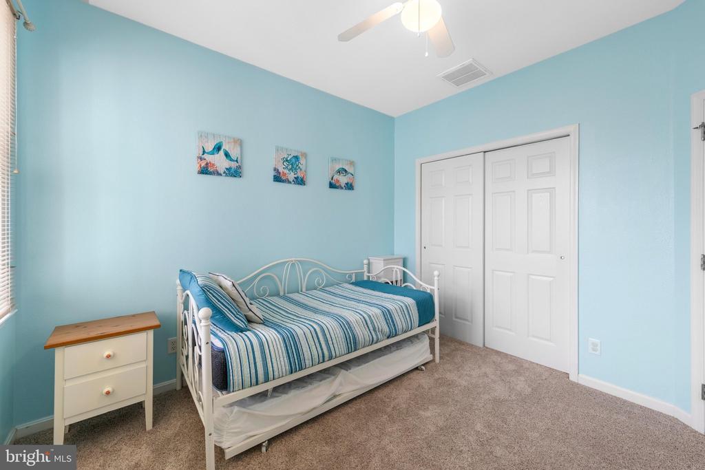 Bedroom with a white metal daybed, blue striped bedding, and light blue walls.