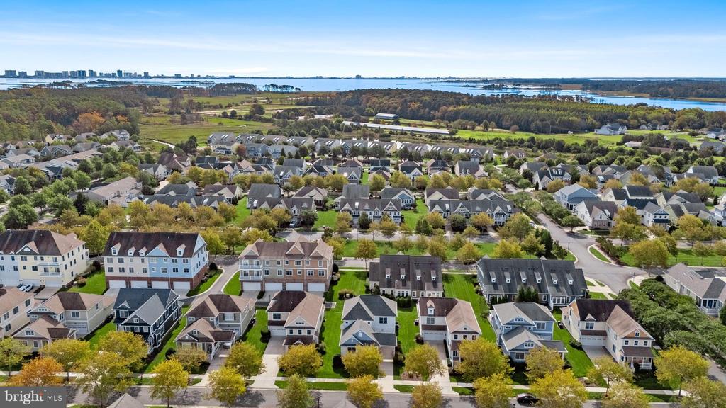 Aerial view of a residential neighborhood with wooded areas and water in the distance