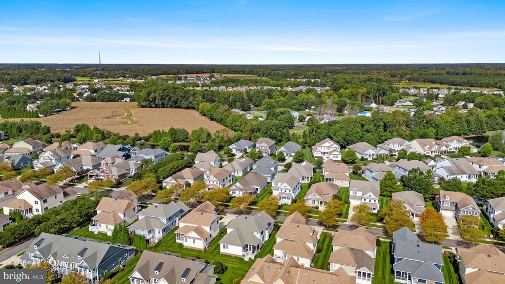 Aerial view of a residential neighborhood beside open fields and wooded areas.