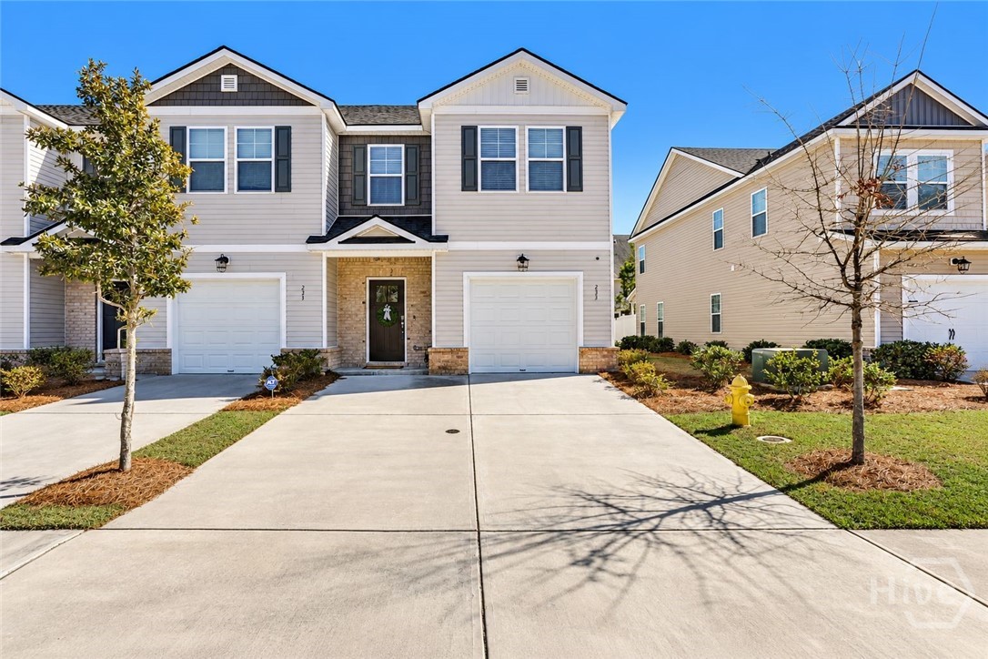 Two-story attached home with a wide driveway, attached garage, and landscaped front yard.