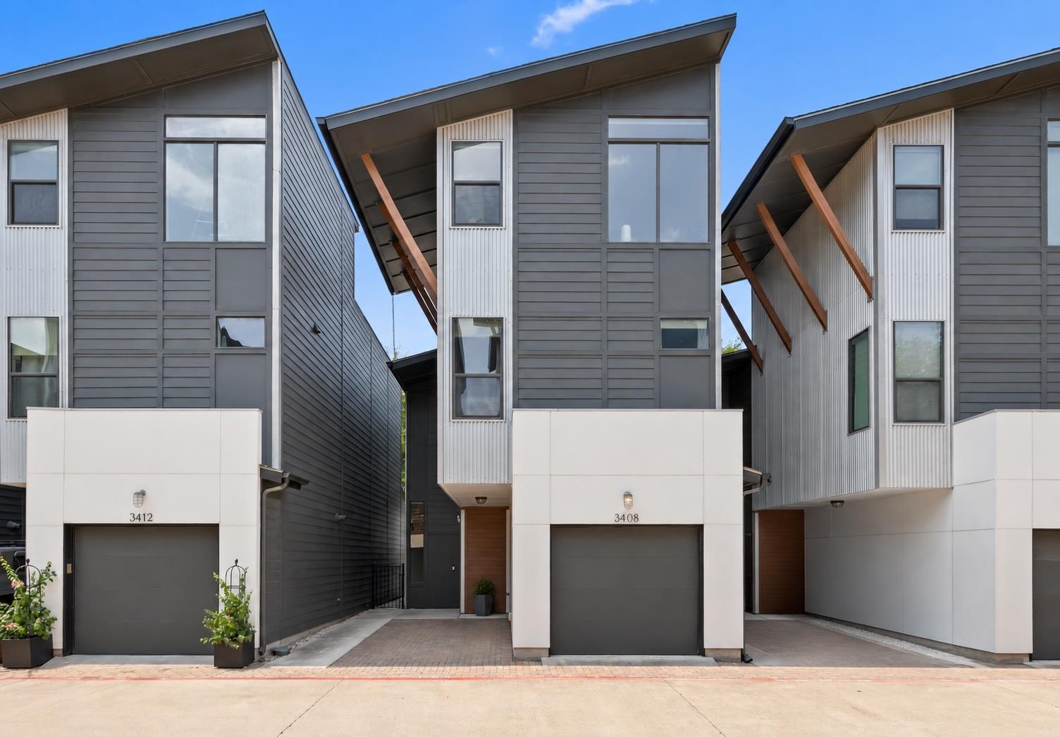 Modern attached townhomes with gray siding and angular roofs; the central garage is marked 3408.
