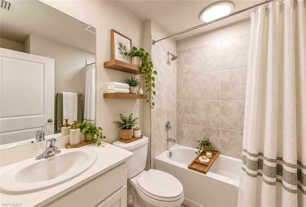Bathroom with a white vanity and tiled bathtub, styled with plants and neatly arranged towels.