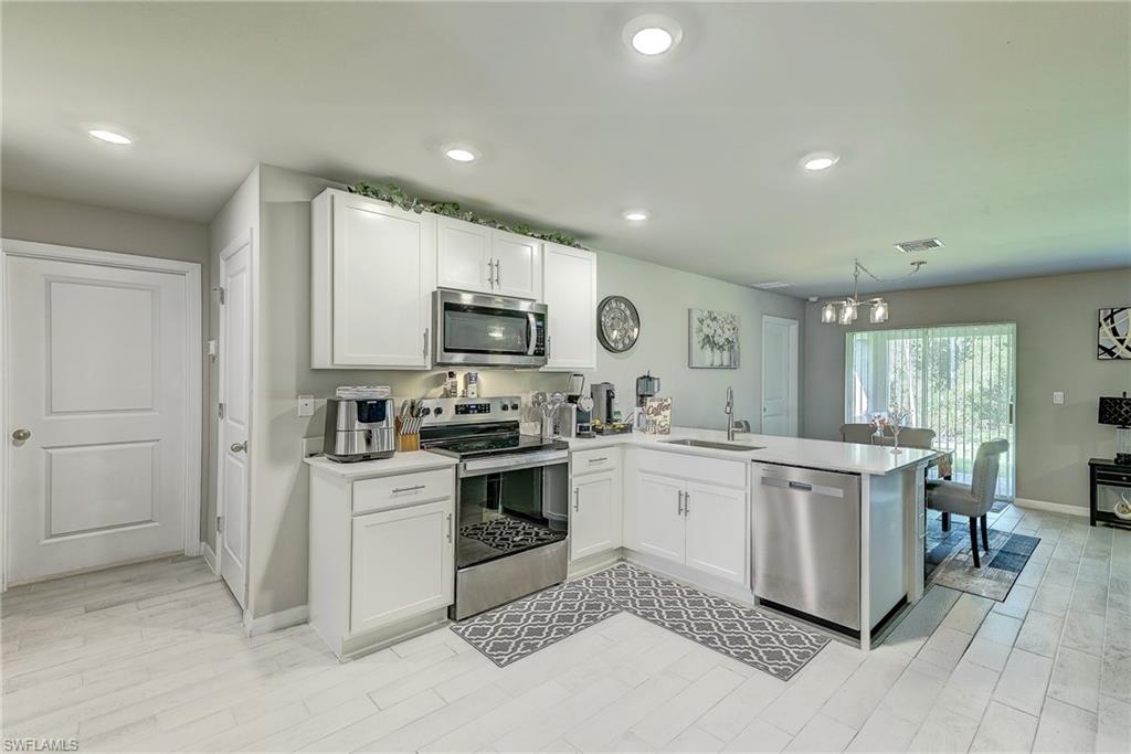 Open-plan kitchen with white cabinets, stainless steel appliances, and a large island.