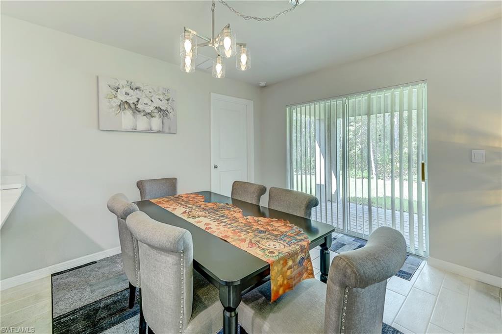 Furnished dining room with a dark table, upholstered chairs, and sliding glass doors opening to a patio.