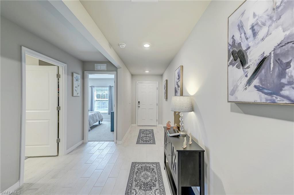 Furnished hallway with white tile floors, patterned runners, and an open doorway to a bedroom.