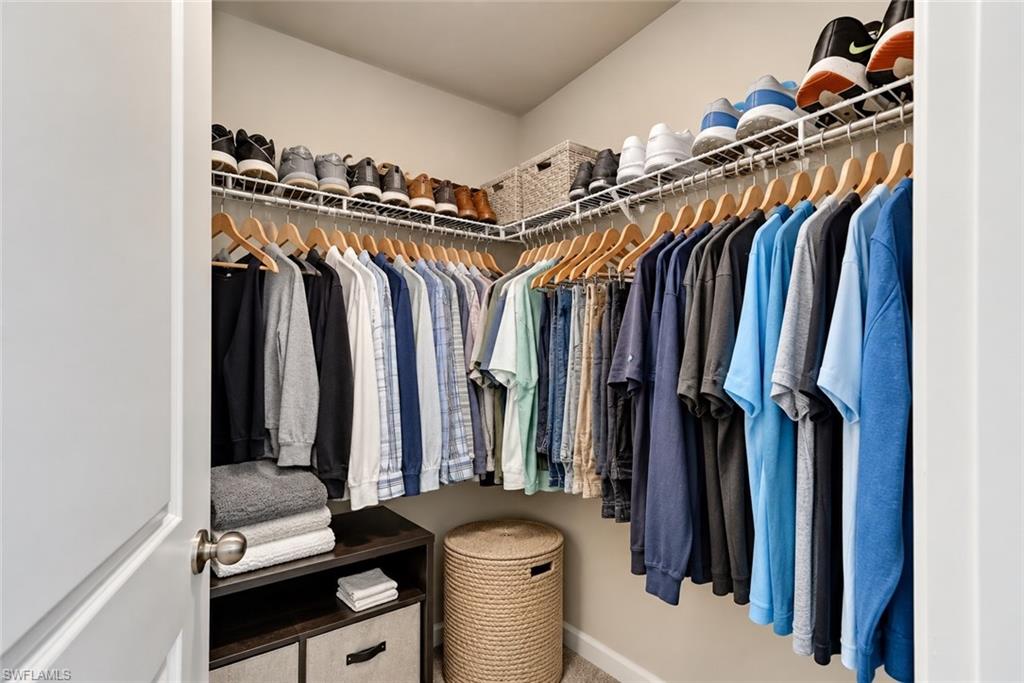 Walk-in closet with wraparound clothing racks, shoe shelves, and a woven hamper.