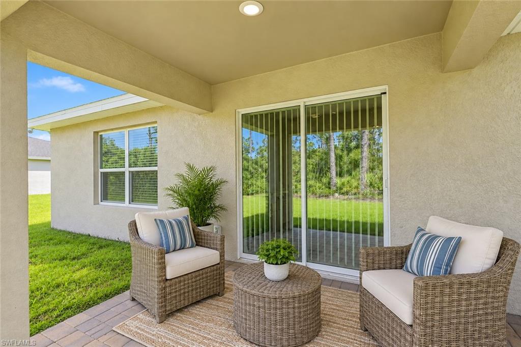 Covered patio with wicker seating and sliding glass doors overlooking a green lawn.