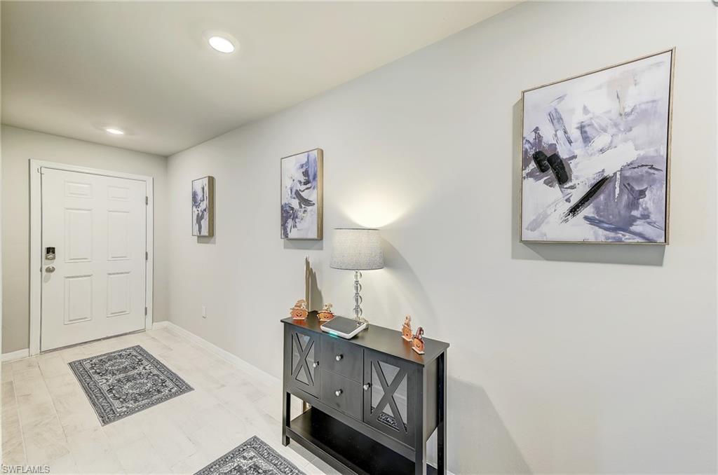 Entry hall with a white paneled door, black console table, lamp, and abstract wall art.