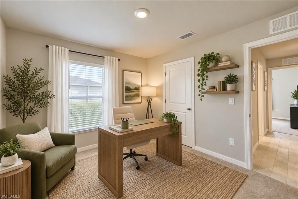 Staged home office with a wooden desk, olive-green armchair, and window with white curtains.