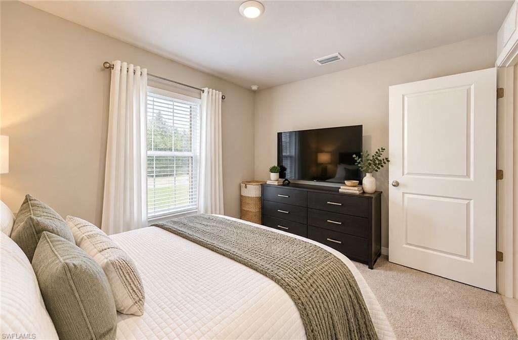 Furnished bedroom with a curtained window and television on a dark dresser.